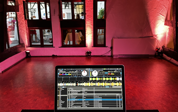 Blick über das DJ Pult auf die beleuchtete Tanzfläche