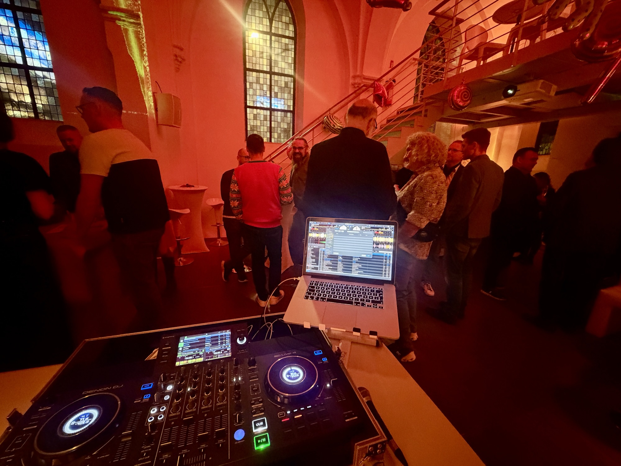Blick über das DJ Pult auf die Gäste im stimmungsvoll beleuchtetem Raum