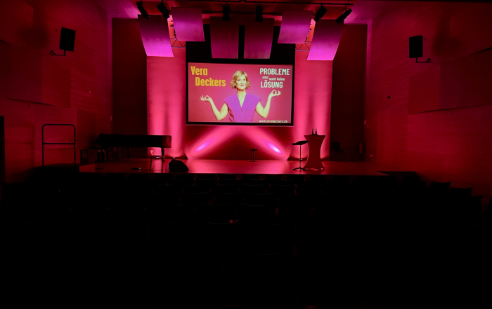 Blick auf eine Bühne mit Leinwand und Wandbeleuchtung