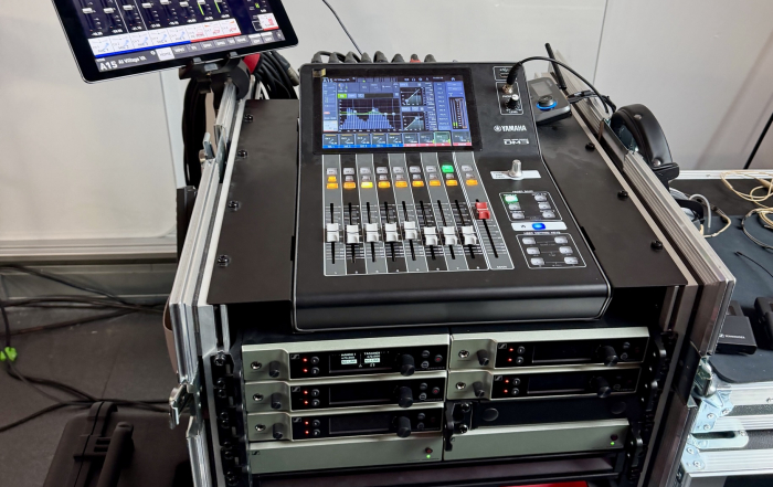 Yamaha-DM3-Digitalmixer mit iPad als Fernbedienung, darunter ein Rack mit mehreren Sennheiser-Funkempfängern