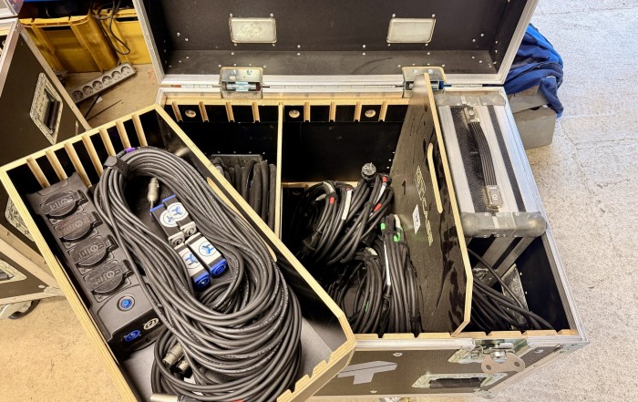 Geöffneter Flightcase mit sauber aufgewickelten XLR- und Lautsprecherkabeln sowie einer Steckdosenleiste mit Powercon-Anschlüssen